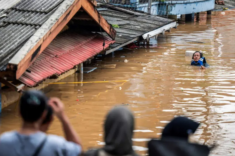 salah seorang warna melintasi banjir. Foto : antara/bayu pratama s.